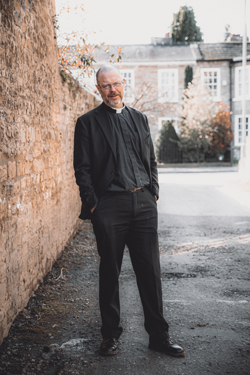 A vicar stands in an alleyway